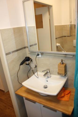 een badkamer met een witte wastafel en een spiegel bij Zentral gelegene Ferienwohnung in Lübeck