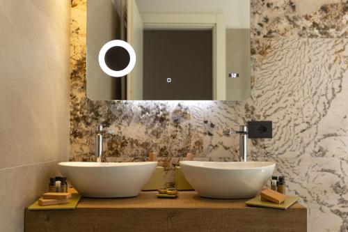 a bathroom with two white sinks and a mirror at Donna Vì Hotel in Geraci Siculo
