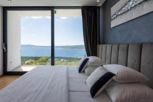 a bedroom with a large bed with a large window at Villa Laurynn with Roof Top Spa and Pool in Crikvenica