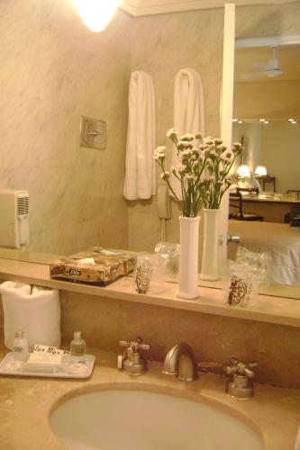 ein Badezimmer mit einem Waschbecken und einer Blumenvase in der Unterkunft Bisonte Palace Hotel in Buenos Aires