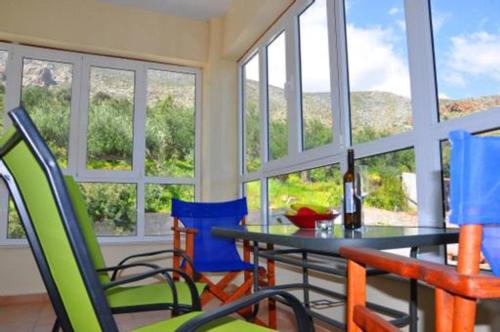 - une salle à manger avec une table, des chaises et des fenêtres dans l'établissement Dimitra Apartments Zakros, à Kato Zakros