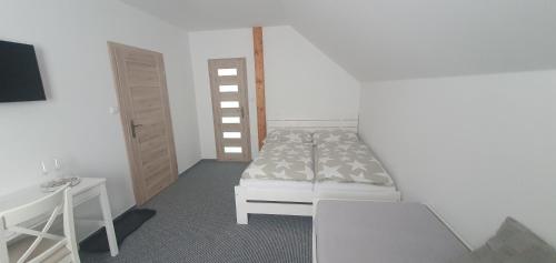1 dormitorio con cama blanca, mesa y silla en Vinný sklep a penzion U Bobule, en Louka