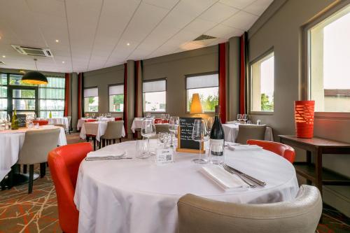 a dining room with a table with white table cloth at Kyriad Prestige Beaune le Panorama in Beaune
