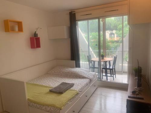 a bedroom with a bed and a table and a window at Les Appartements De Lina - Self Check-In in La Grande-Motte