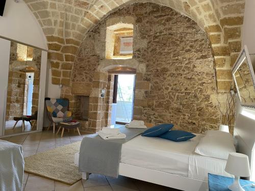 1 dormitorio con 1 cama grande en una pared de piedra en DIMORA SPACCAMONTI en Torchiarolo