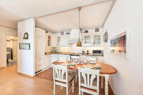 cocina con mesa de madera y armarios blancos en Nordseeblick Nordseeblick 111, en Norderney