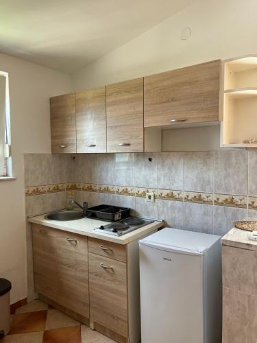 a kitchen with wooden cabinets and a white refrigerator at Apartments Villa Sveti Nikola in Budva
