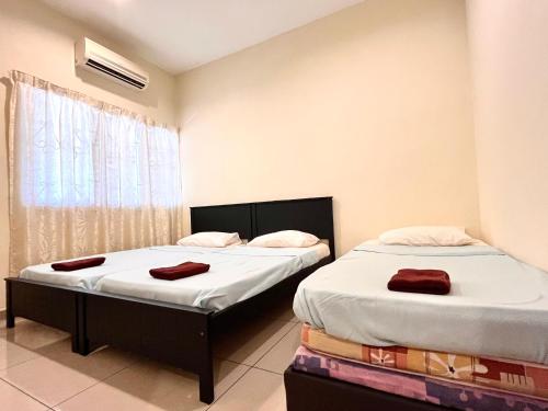 two twin beds in a room with a window at VGO House in Malacca