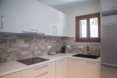 a kitchen with white cabinets and a sink and a window at Ilenia Guesthouse in Zagora