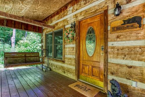 a wooden cabin with a wooden door and a bench at Bear Hug Too Cabin in Line Spring