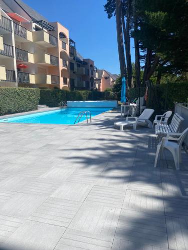 une piscine avec deux chaises blanches et une piscine dans l'établissement Appartement La Baule;Pornichet, à La Baule