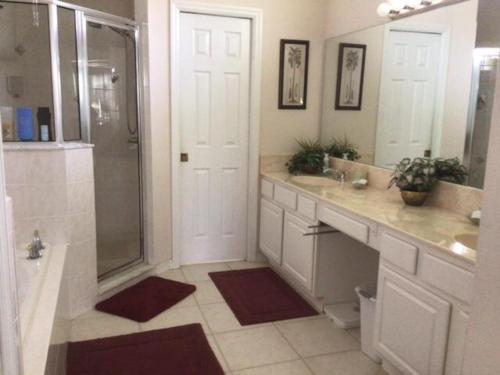 uma casa de banho com um chuveiro, 2 lavatórios e uma porta traseira de chuveiro. em Villa Merlin em Davenport