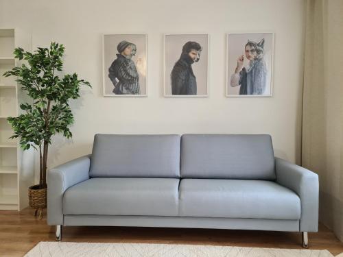a couch in a living room with three pictures on the wall at Moon apartments in Anykščiai