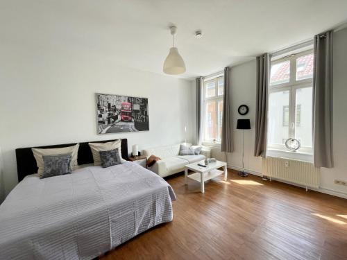 a white bedroom with a bed and a couch at City-Apartment nahe Zentrum in Schwerin