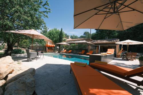 a swimming pool with chairs and umbrellas and a swimming pool at Ekin ô reV Gîte Fontessante in Montauroux