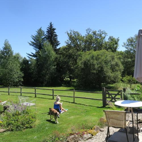 a woman sitting in the grass with a dog at Sérénité Verte à La Tuilerie Accommodation in La Bazeuge
