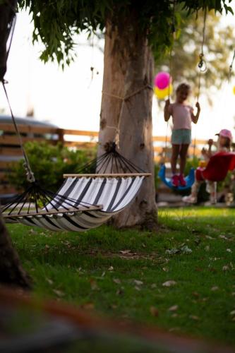 a girl playing with a ball in a hammock next to a tree at Delfini Hotel in Patra