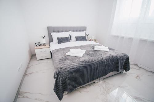 a white bedroom with a large bed with marble floors at L Apartment in Maribor