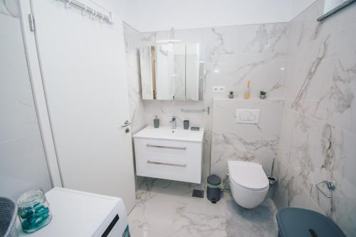 a white bathroom with a toilet and a sink at L Apartment in Maribor