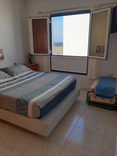 a bedroom with a bed and a large window at Apartamento vacacional en Orzola Lanzarote in Orzola