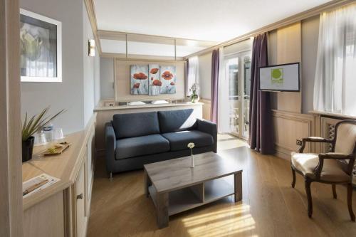 ein Wohnzimmer mit einem blauen Sofa und einem Tisch in der Unterkunft Cottage Logis Hôtel - Restaurant in Dudelange