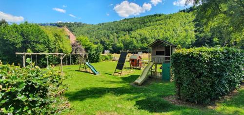 a yard with a swing set and a playground at cosy holiday home with sauna near river in La Roche-en-Ardenne