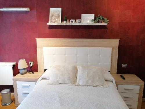 a bedroom with a white bed and a red wall at Apartamento Maracaibo in Astorga