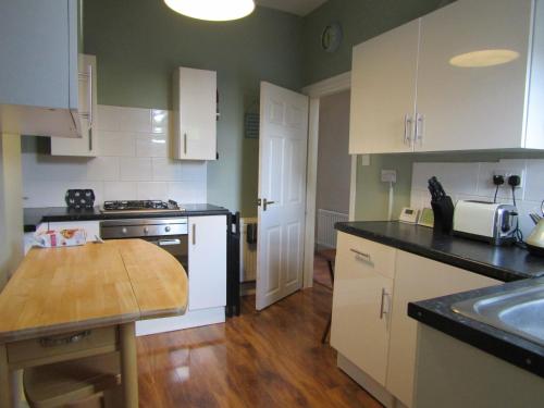 a kitchen with white cabinets and a wooden table at Woolly Hill House - Beautiful Townhouse in the Heart of Wooler in Wooler