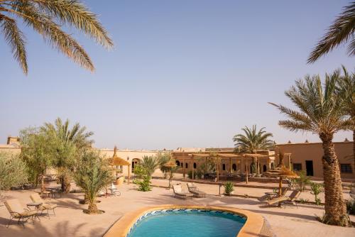 a resort with a swimming pool and palm trees at RiadSuerteloca Merzouga in Merzouga