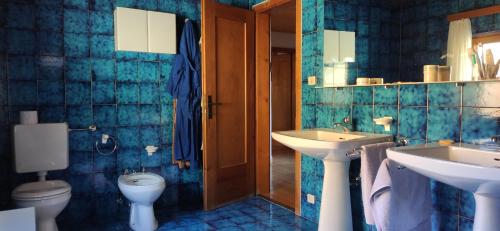 a blue tiled bathroom with two sinks and a toilet at Villa for a get away in Soprabolzano