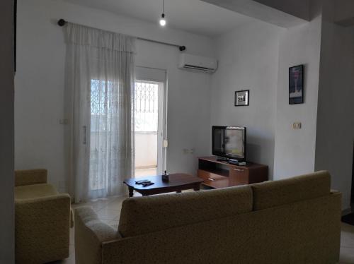 uma sala de estar com um sofá e uma televisão em Sweet Apartment em Saranda