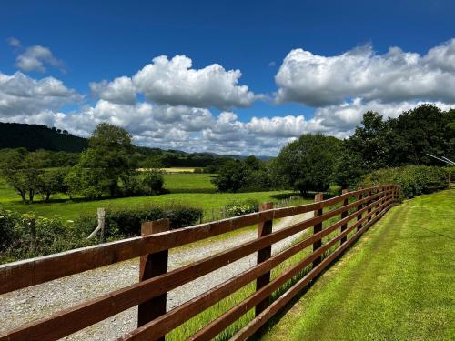 a wooden fence next to a field with trees at Cwmgwn Farm in Llandovery