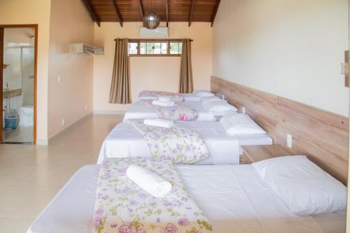 una fila de camas blancas en una habitación en Pousada dos Guias, en Alto Paraíso de Goiás