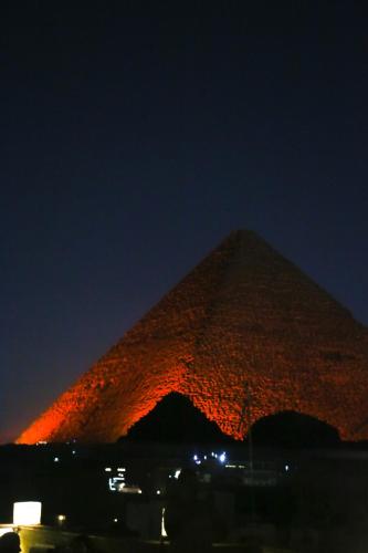 a pyramid is lit up at night at Pyramids Valley Boutique Hotel in Cairo