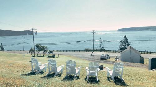 a group of white chairs sitting on top of a field at À Bon Port in Perce