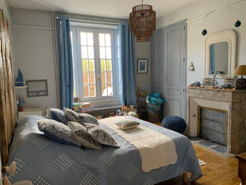um quarto com uma cama com almofadas e uma lareira em La Terrasse de Compostelle T3 Chic, Charme, Cosy em Saint-Léonard-de-Noblat