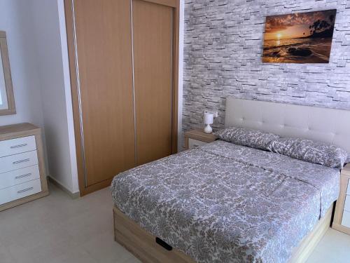 Un dormitorio con una cama y una pared de ladrillo. en Ruben House, en Vera