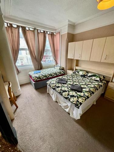 two beds in a room with two windows at Hayward Hotel in Blackpool