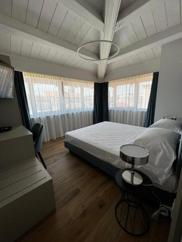 a bedroom with a bed and a table and some windows at C House Rooms Lake in Peschiera del Garda