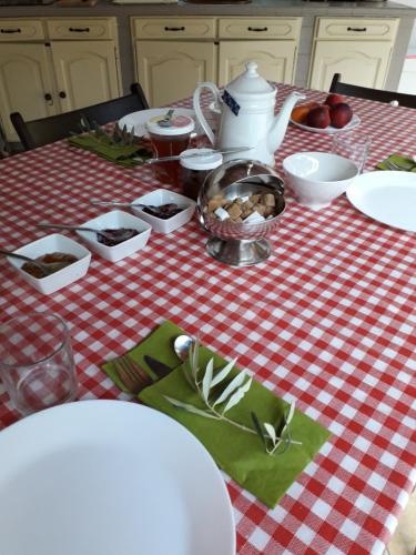 une table avec un chiffon de table rouge et blanc dans l'établissement LES RESTANQUES - Chambre d'hôtes, à Cuges-les-Pins