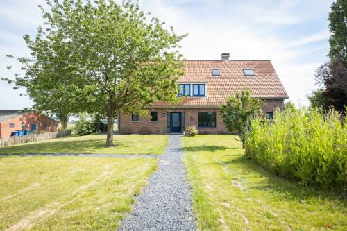 una casa con un árbol en medio de un patio en Blauwe Hoeve Luxe, ruimte, privacy en rust, en Retranchement