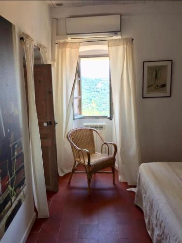 a bedroom with a chair and a window at Casa Divota au cœur d’un village paisible in Santa-Reparata-di-Balagna