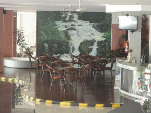 a dining room with chairs and a painting of a waterfall at Jóia Hotel in Poços de Caldas