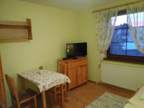 a small dining room with a table and a television at Pod palmou Gerlachov in Gerlachov