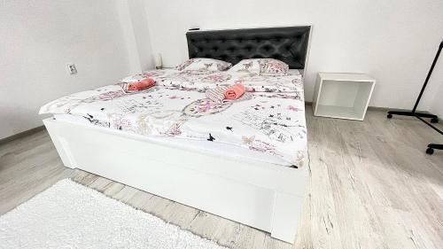 een slaapkamer met een wit bed met roze bloemen erop bij Apartament linistit / Cozy apartment in Câmpulung Moldovenesc