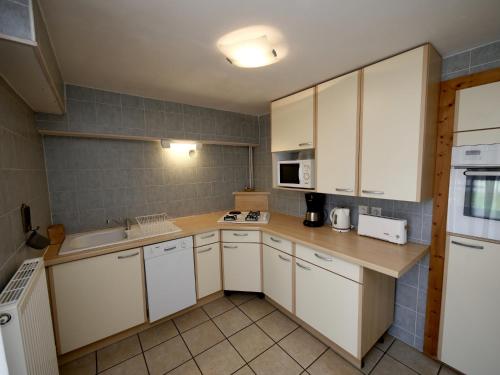 une cuisine avec des armoires blanches et un évier dans l'établissement Chalet Crocus Studio, à Huez