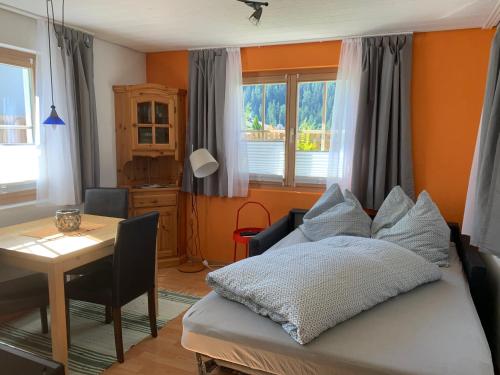 a bedroom with a bed and a table and window at Chasa Bazzi in Scuol