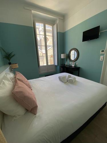 a bedroom with a large white bed with a window at Hotel De L'Océan in Biarritz