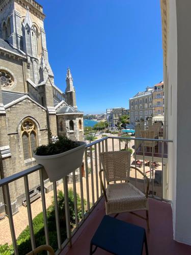 a balcony with two chairs and a church at Hotel De L'Océan in Biarritz