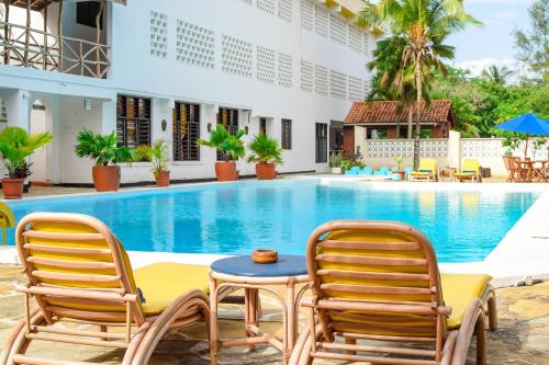 a resort with a swimming pool and two chairs and a table at Kahama Hotel Mombasa in Bamburi